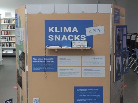 Eine Ausstellungswand zeigt viele verschiedene Bilder und Texte, zu lesen ist die große Überschrift "Klima Snacks"
