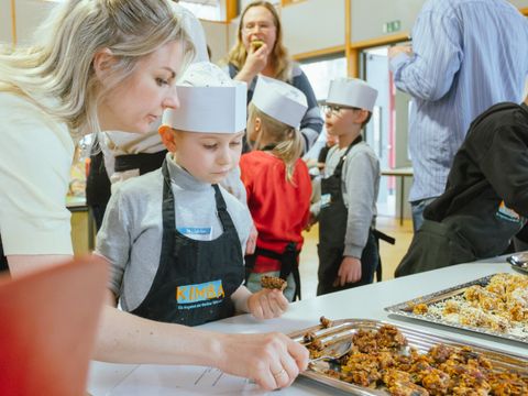 Eine Frau und ein Junge mit Kochmütze und Kochschürze an einem Buffet mit Snacks
