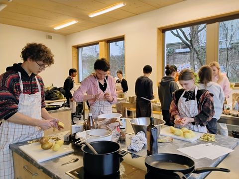 Mehrere Personen bereiten gemeinsam Speisen in einer Küche zu