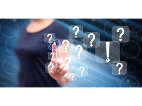 Frau steht vor einem Bildschirm voller Fragezeichen