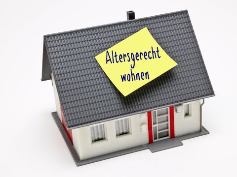 Symbolbild mit einem Modellhaus auf dem ein Zettel mit der Aufschrift 'Altersgerecht wohnen' klebt