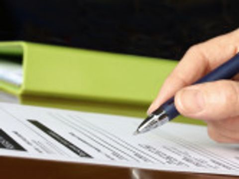 Hand with Pen Signing Form by Green Folder