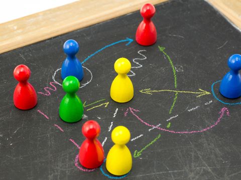 Spielfiguren auf einer Tafel verbunden mit Kreidelinien