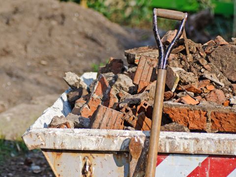 Bauschuttcontainer gefüllt mit zerbrochenen Ziegeln und Steinen