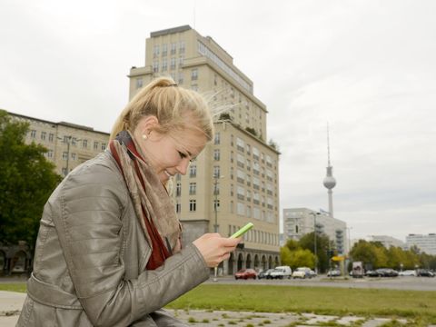 Junge Frau mit Smartphone, Strausberger Platz, Berlin