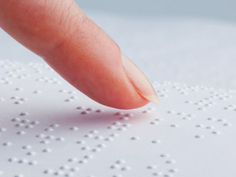 Zeigefinger fährt über Brailleschrift