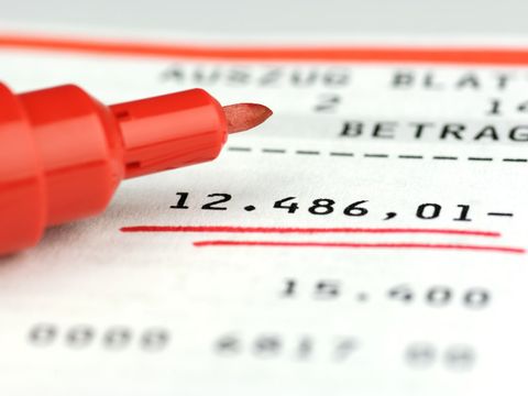 Kontoauszug zeigt einen unterstrichenen Minusbetrag von 12486,01 Euro an, daneben liegt ein Filzstift