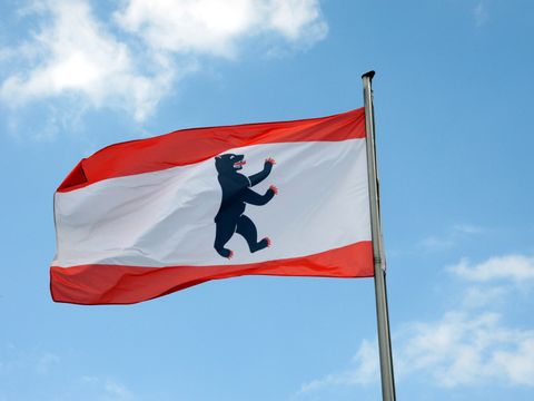 Landesflagge von Berlin mit einem zum Fahnenmast schauenden Berliner Bären