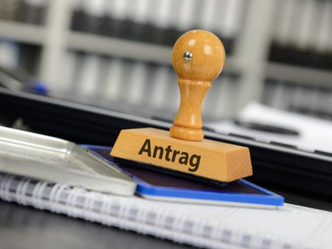 Stempel mit der Aufschrift 'Antrag' steht auf einem Stempelkissen