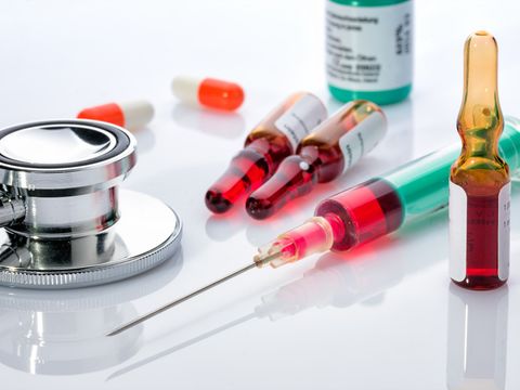 Ampullen, Spritze, Stethoskop und Tabletten liegen auf einem Tisch
