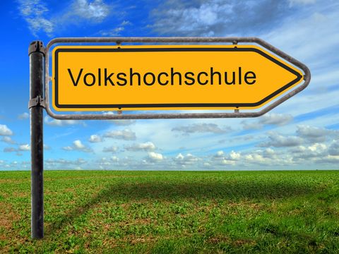 Schild mit Aufschrift "Volkshochschule" auf einer Weise