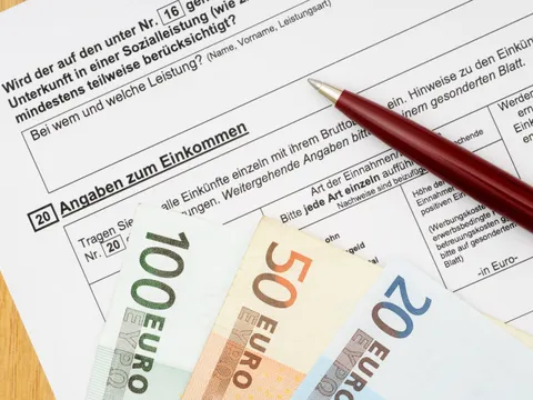 Geldscheine und ein Stift liegen auf einem Wohngeldantrag