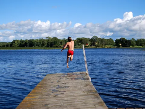 Vergnügen. Junge springt ins kühle Wasser