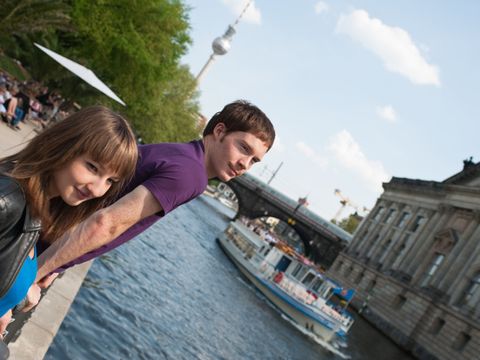 Junges Pärchen steht an der Spree, im Hintergrund der Fernsehturm