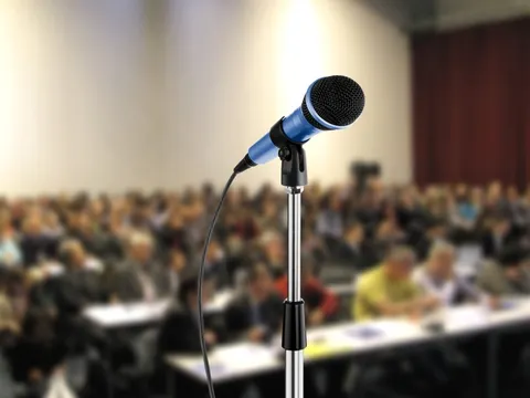 Mikrofon vor einem Hörsaal mit Menschen