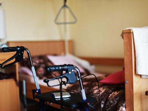 Zimmer im Altenheim. Im Vordergrund ist ein Rollator zu sehen.