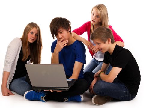 Eine Gruppe Teenager hat sich zum Thema Cybermobbing vor einem Laptop versammelt