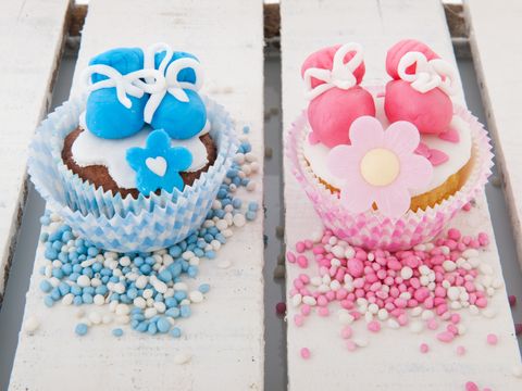 Zwei Cupcakes dekoriert mit blauen und rosa Babyschühchen