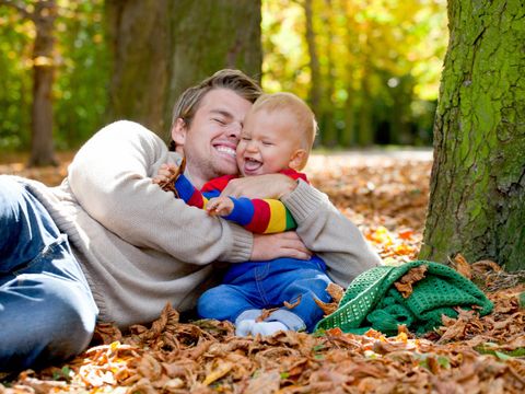 Vater spielt mit Kleinkind auf Waldboden