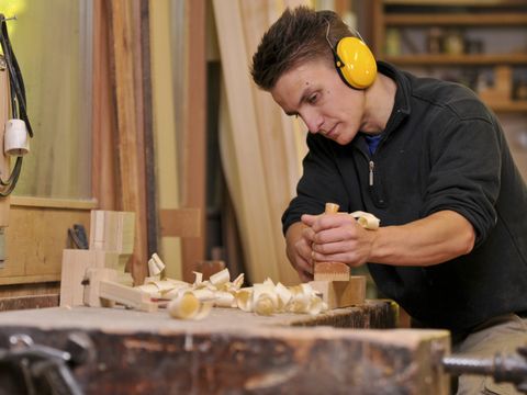Jugendlicher der Holz hobelt