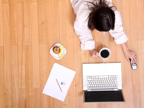 Mädchen liegt vor dem Laptop auf dem Boden