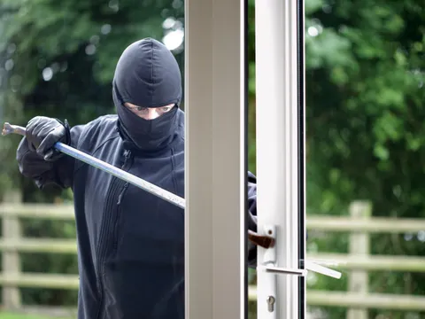 Ein Einbrecher hebelt eine Glastür auf