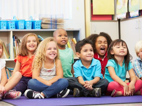 8 Kinder sitzen auf einer Matte