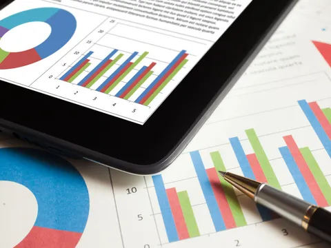 Statistische Aufbereitung auf Blatt mit Kugelschreiber und einem Tablet darüber liegend