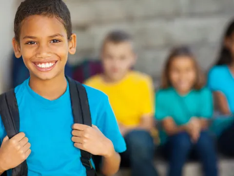 fröhlicher Junge im Vordergrund scharf und im Hintergrund 3 lachende Kinder unscharf fotografiert