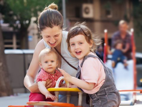 Mutter mit zwei Kindern auf dem Spielplatz