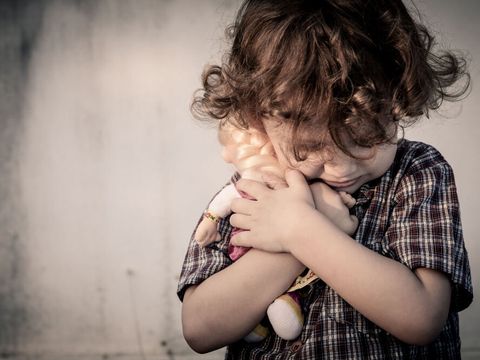 Trauriger kleiner Junge mit Puppe im Arm