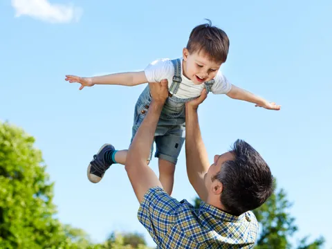 Vater wirft Sohn mit Freude in die Luft