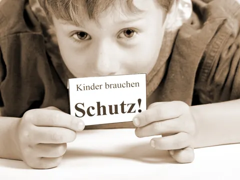Junge mit Schild - Kinder brauchen Schutz