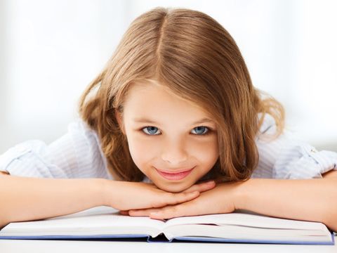 Mädchem liegt auf einem Stapel Büchern