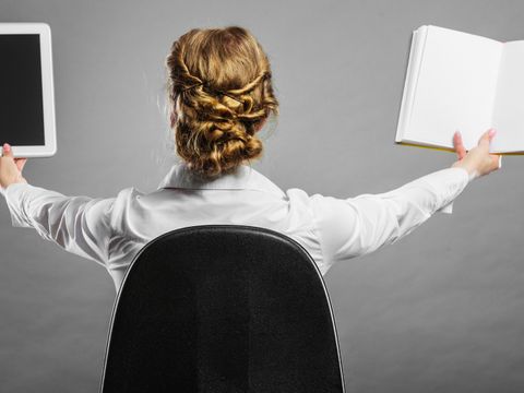 Frau hält ein Buch und ein Tablet hoch