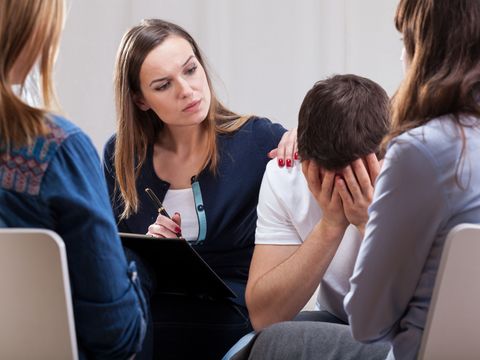 Eine Psychotherapeutin tröstet einen Patienten während einer Gruppentherapie