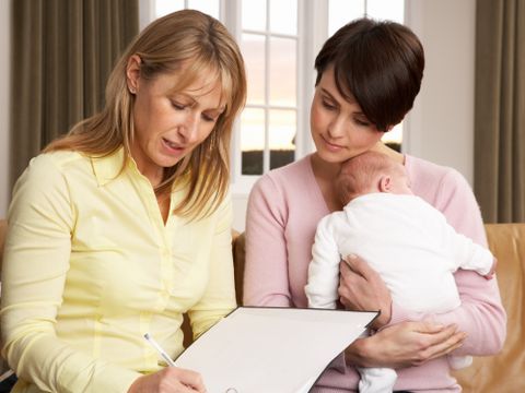 Eine Hebamme spricht mit einer Mutter, die ihr Kind im Arm hält