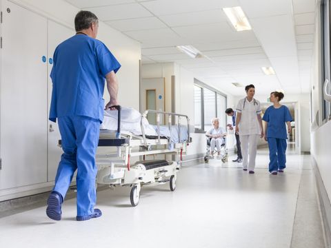 Mediziner schiebt Krankenbett durch Krankenhausflur
