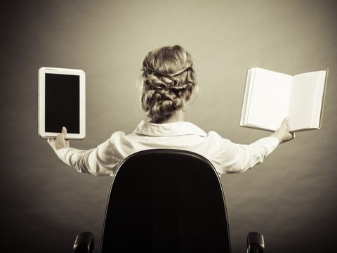 Frau hält ein E-Book-Reader und ein Buch hoch