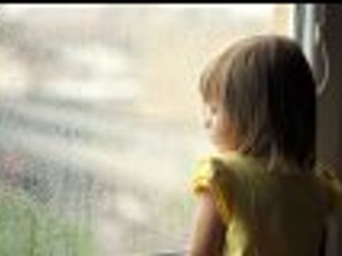 Kind stehend am verregnetem Fenster