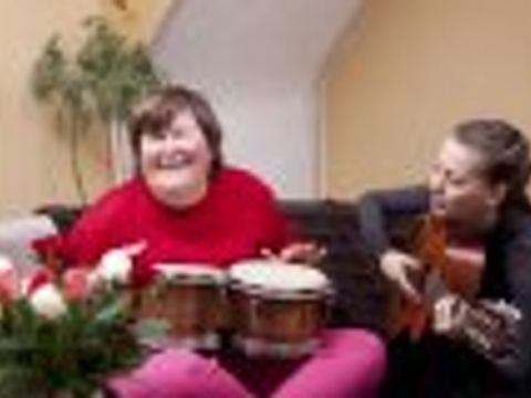 Eine Frau mit Trommeln und eine Frau mit Gitarre musizieren zusammen