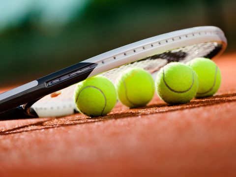 Ein Tennisschläger und vier Tennisbälle
