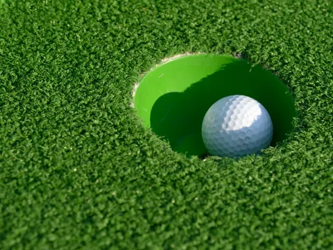Minigolfball ist auf einer grünen Bahn eingelocht