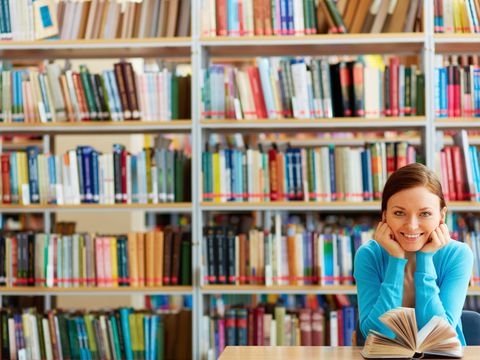 Junge Frau mit vielen Büchern im Hintergrund