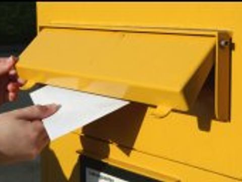 Brief wird in Briefkasten eingeworfen