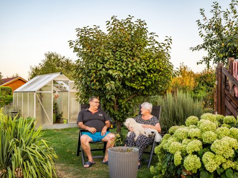 Zwei Personen mit Hund sitzen in einem Kleingarten in der KGA Am Kienberg