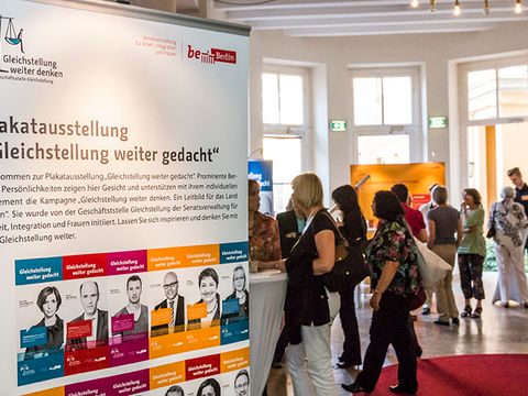 Im Vordergrund Plakat mit öffentlichen Personen, die die Kampagne unterstützen