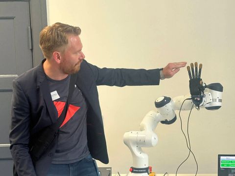 Ein junger Mann berührt während einer Präsentation eine Hand eines Roboters