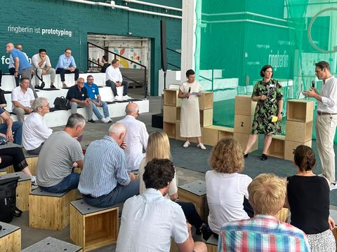 Eine Präsentation von 3 Personen vor einer Gruppe Zuhörern