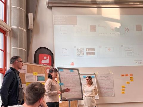 Drei Mentoren vor Whiteboards, die mit Postits beklebt sind